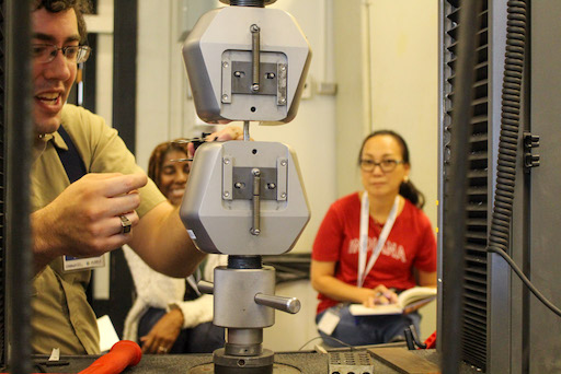 instructor uses a tensile testing device while visiting educators watch