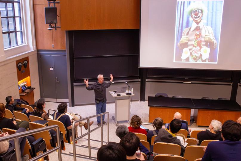 person presenting in an auditorium displaying a clown picture