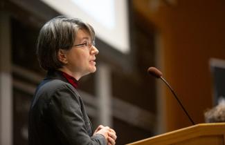Bilge Yildiz standing at a podium giving a speech.