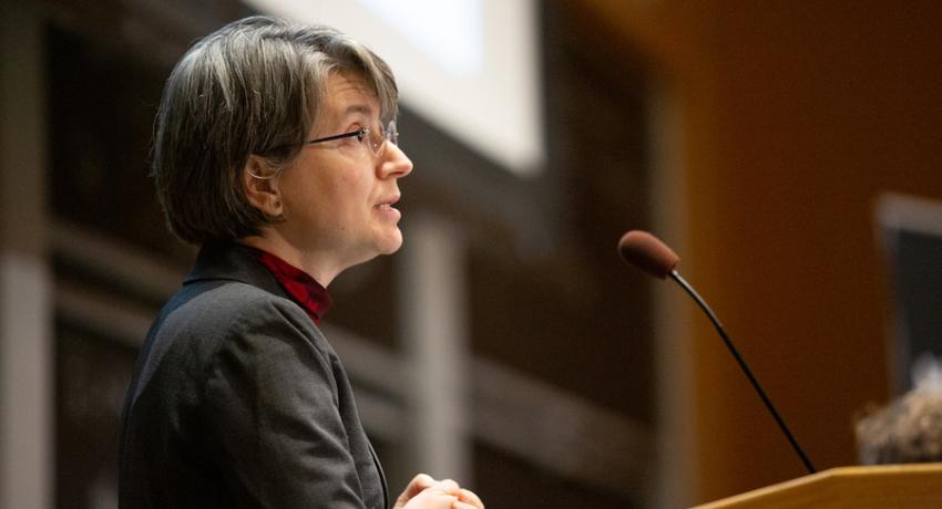 Bilge Yildiz standing at a podium giving a speech.