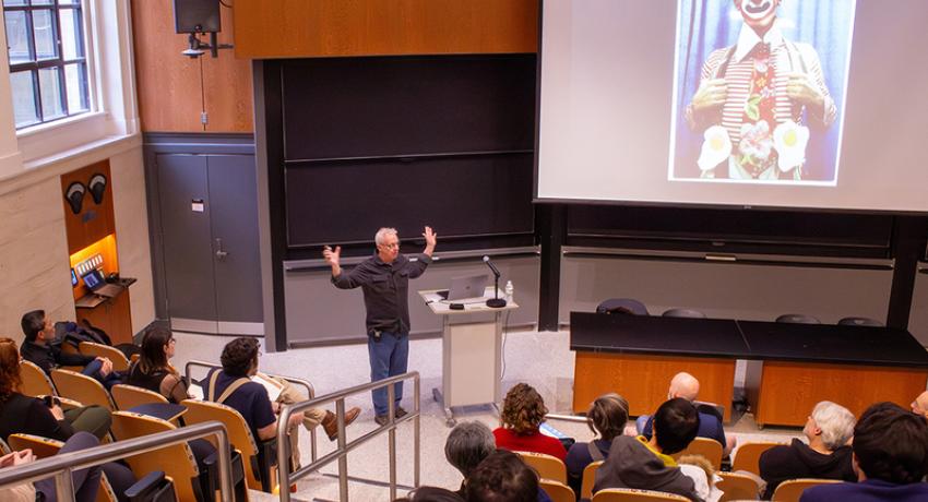 person presenting in an auditorium displaying a clown picture