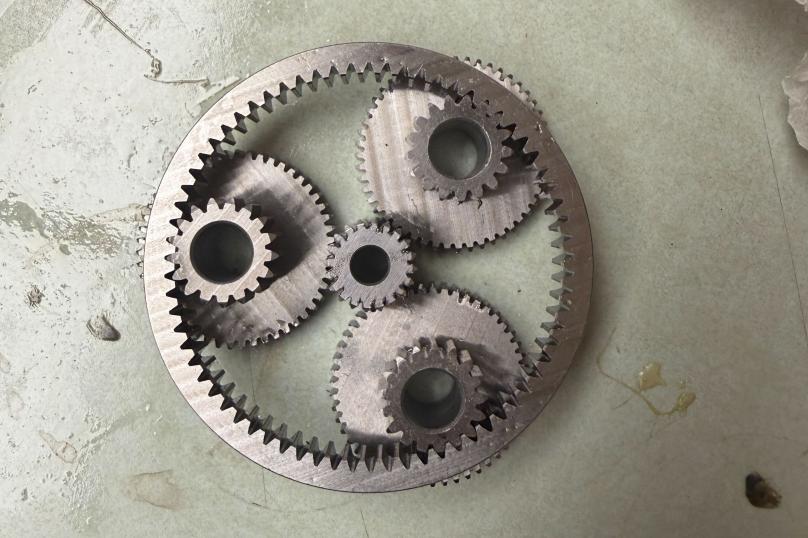 Planetary gearbox with three planetary gears around one sun gear, all contained within one larger outer ring.