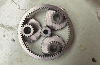 Planetary gearbox with three planetary gears around one sun gear, all contained within one larger outer ring.