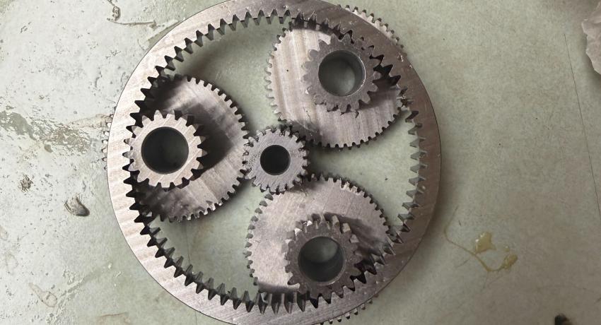 Planetary gearbox with three planetary gears around one sun gear, all contained within one larger outer ring.